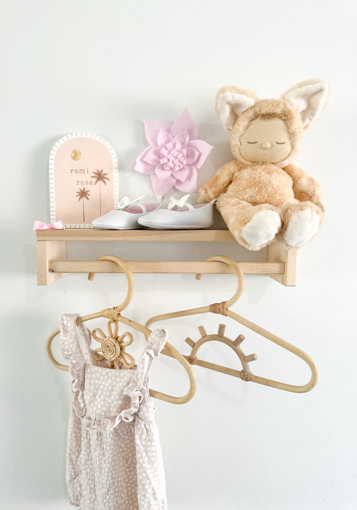 handmade child's flower rattan wardrobe hanger with clothes handing on shelf with other decorative children's items