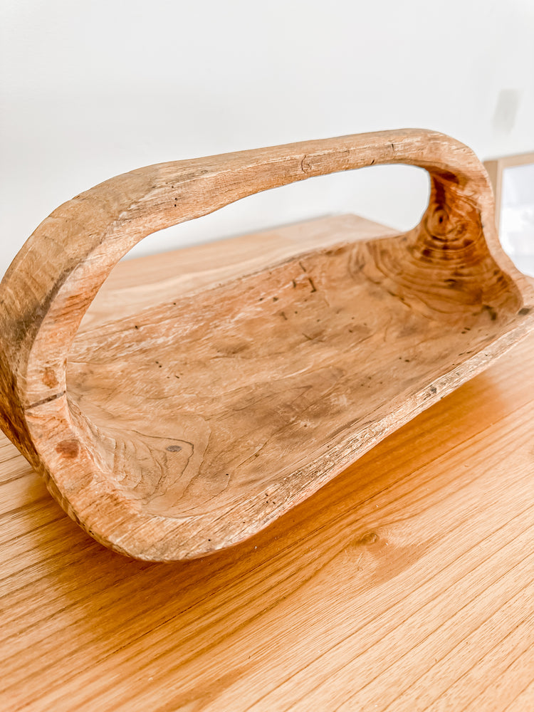 Wooden teak oblong basket with handle sitting on wooden shelf