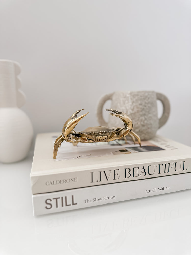 Brass crab displayed on two books with a small vase containing flowers