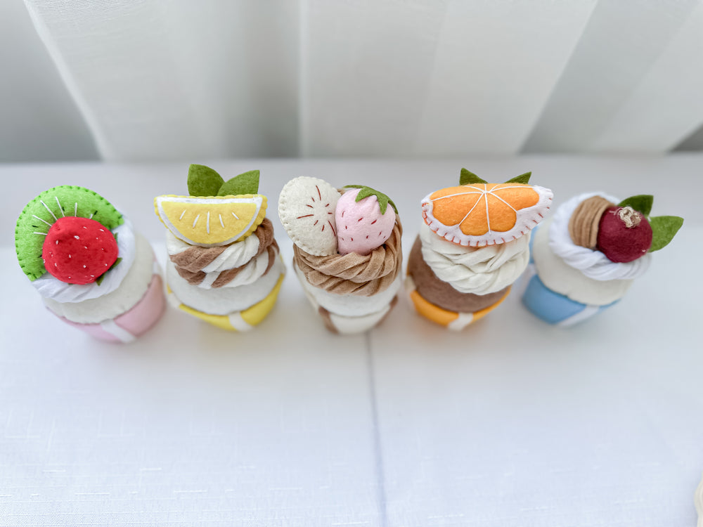 Set of five different coloured felt cupcakes with various toppings