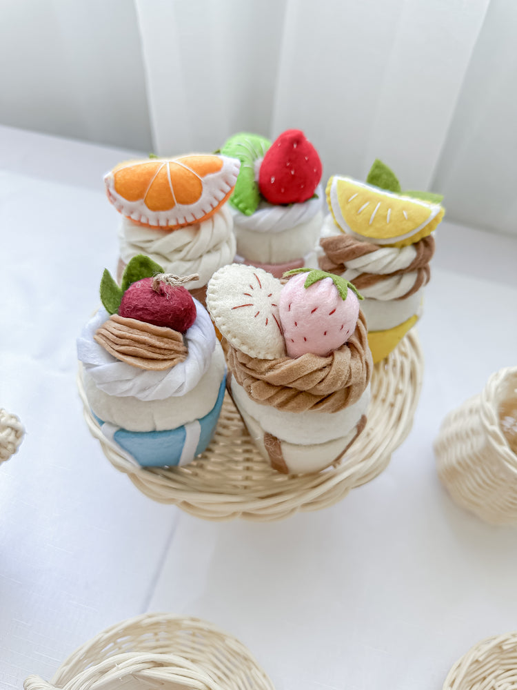 Top view of five felt cupcakes on a rattan tray