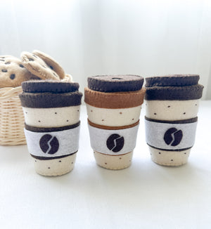 Three felt coffee cups with lids in mocha and latte colours with two chocolate chip felt cookies in a basket.