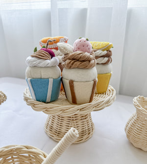 Set of four colourful felt cupcakes on a rattan cake tray