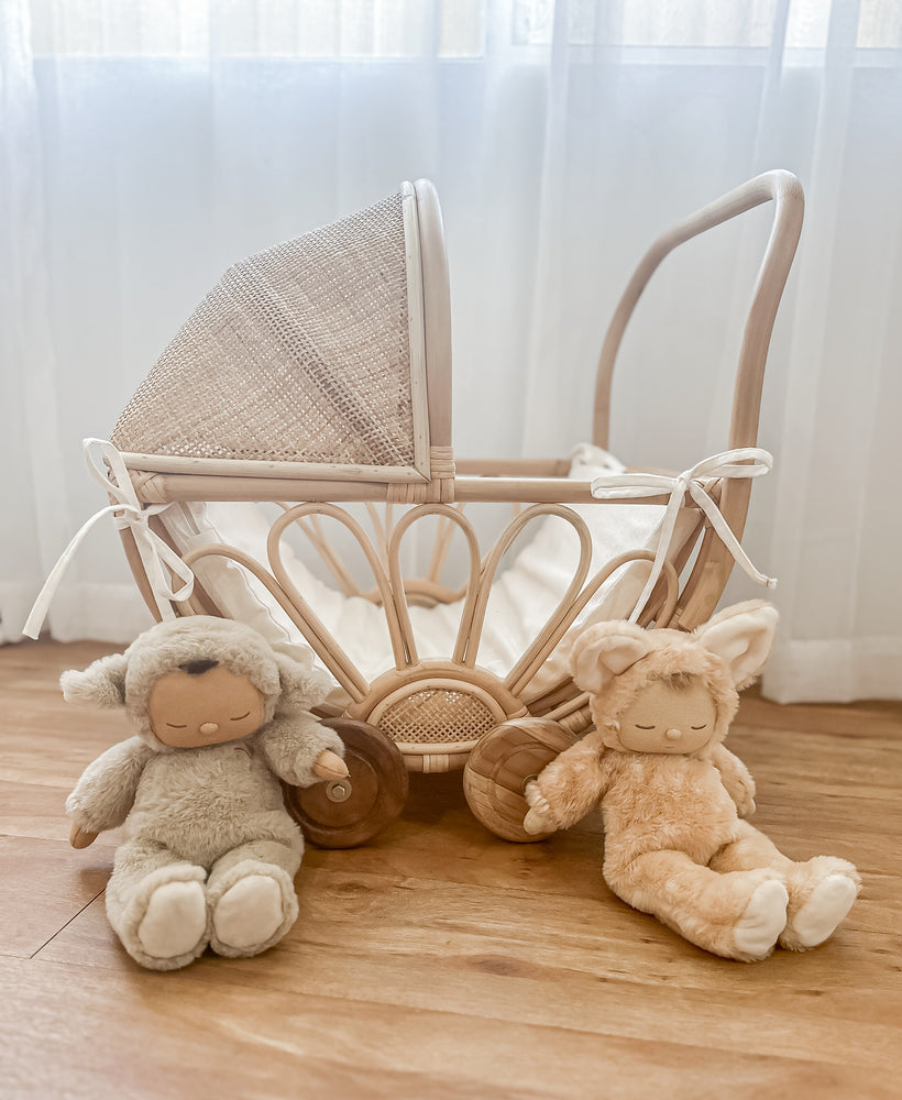 Rattan dolls pram with insert and two dolls sitting on floor in front of pram 