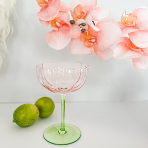 Pink and green Tulip glasses on a table with limes and flowers