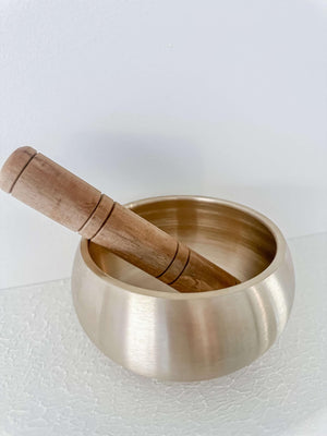 Brass singing bowl with small wooden mallet inside bowl