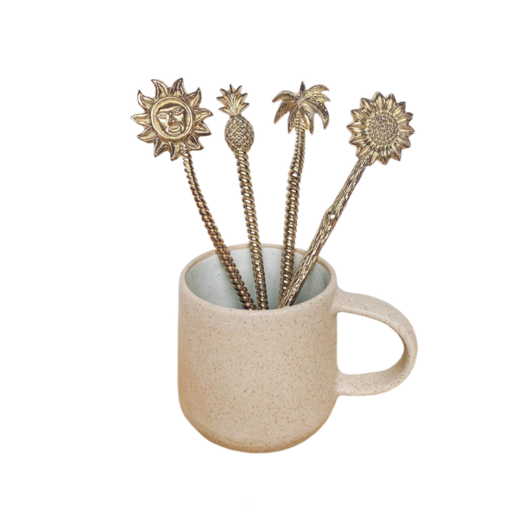 Sun, pineapple, palm tree and sunflower brass spoons displayed in a mug