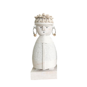 white doll with macramé body, shell hat and earrings with beads on a wooden stand