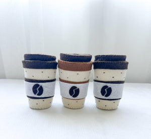 Three felt coffee cups mixed colours mocha latte kids toys grey background