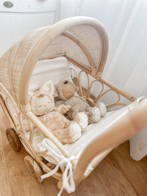 Handmade rattan play dolls pram Violet with two dolls seated inside - premium Balinese artisan toy featuring teak wooden wheels and soft foam linen insert