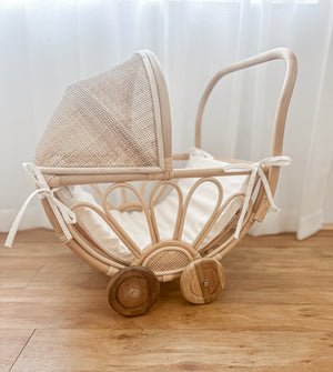 Rattan play dolls pram Violet with foam insert on wooden floor in natural light - handmade Balinese artisan children's toy with teak wheels