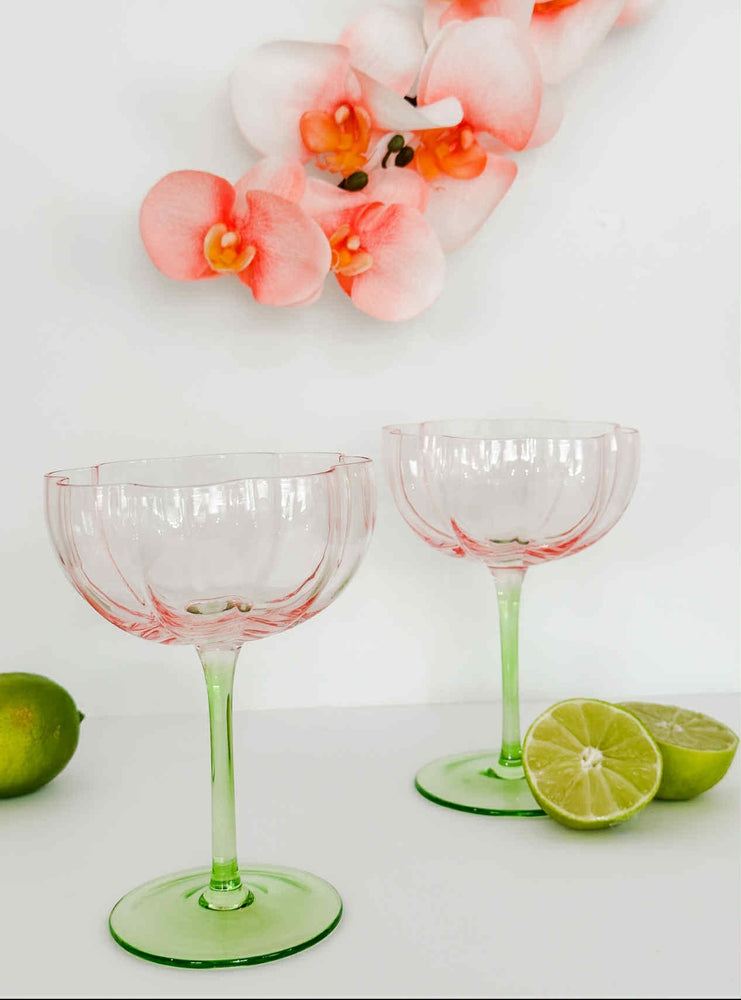 Two pink and green Tulip wine glasses styled on table with fresh limes and flowers for summer entertaining