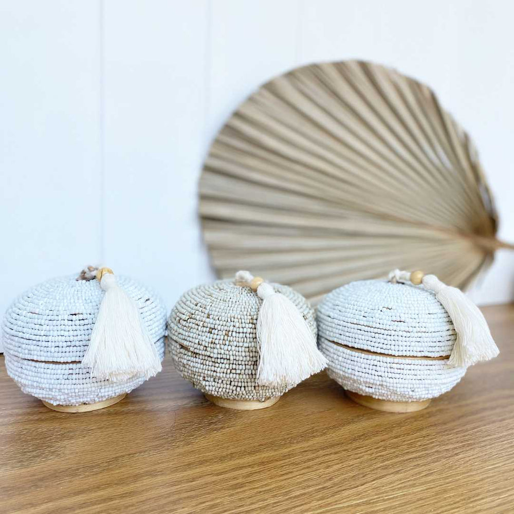 three beaded boxes with tassels on unit