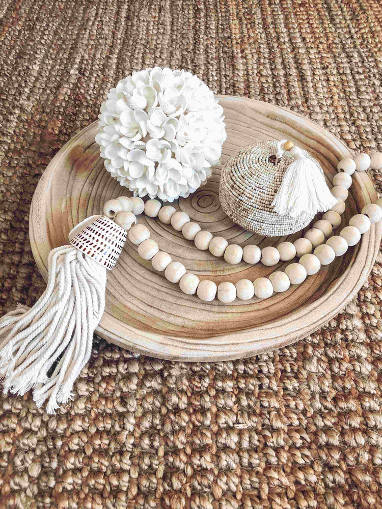 white frangipani shell ball displayed on wooden tray