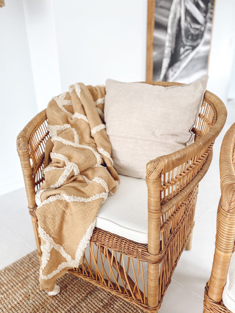 Cotton tufted throw Marlee in butterscotch colour on rattan chair with  cushion and wall picture