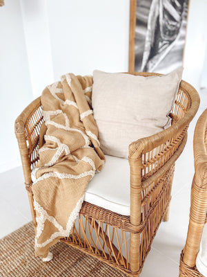 Cotton tufted throw Marlee in butterscotch colour on rattan chair with  cushion and wall picture
