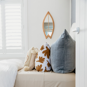 rattan surfboard mirror on bedroom wall over a bed