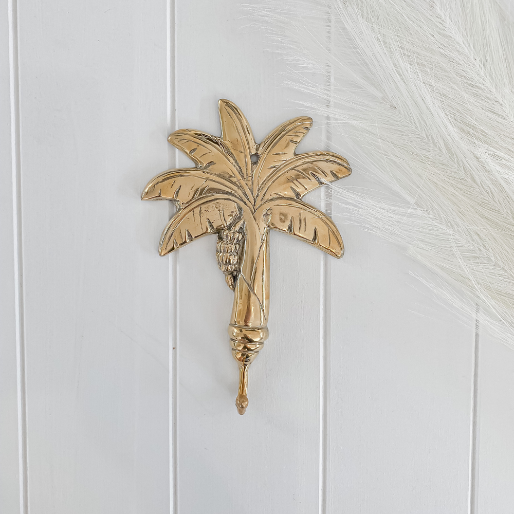 Brass palm tree hook on white wall