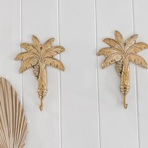 Two brass palm tree hooks on wall