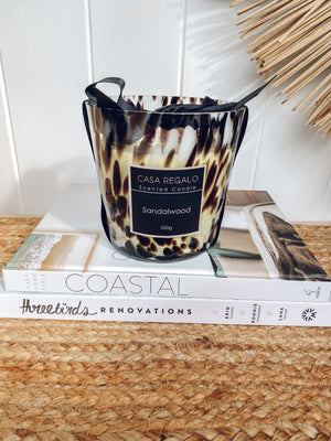 Casa Regalo 550g Sandalwood scented candle in black patterned glass jar displayed on renovation book