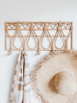 Rattan wall hanger on wall with a hat and scarf