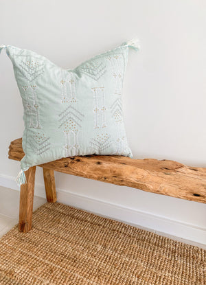 square cushion cover with tassels on wood bench