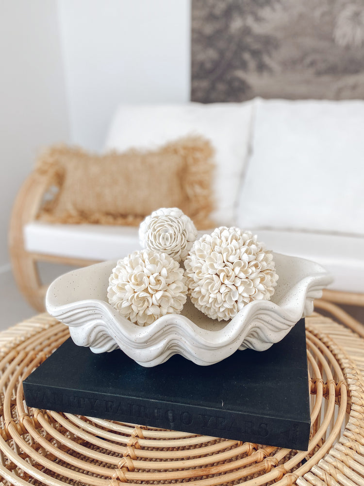 three frangipani shell balls displayed in ceramic bowl