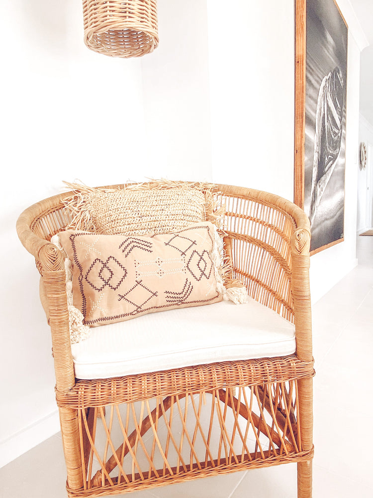 lumber cushion with tassels on rattan chair