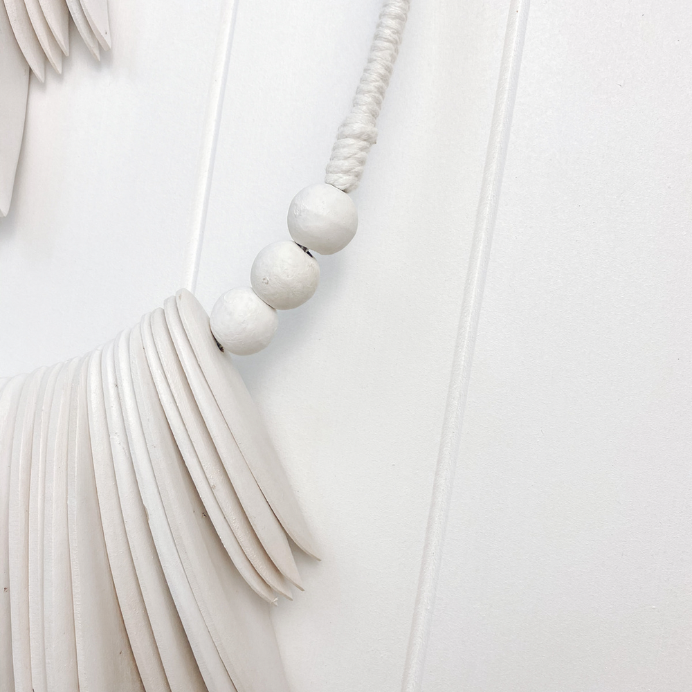 close up of white timber with beads wall hanging