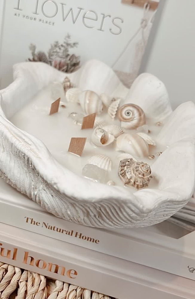 Handmade candle with shell and stones in a large bowl displayed on design books