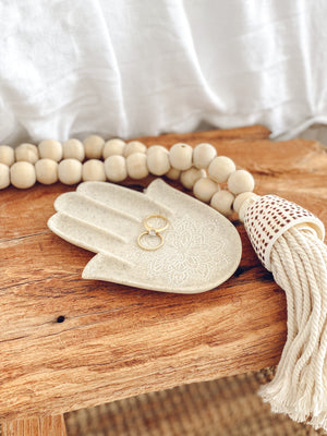sandstone trinket dish displayed with jewellery and shell tassel on a wooden bench