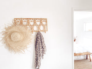 Rattan wall hanger on wall with hat and scarf