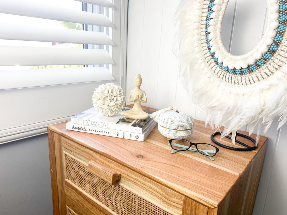 Small yoga lady on bedside table with shell ball, beaded basket, books and glasses - peaceful bedroom meditation decor styling