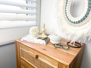 Small yoga lady on bedside table with shell ball, beaded basket, books and glasses - peaceful bedroom meditation decor styling