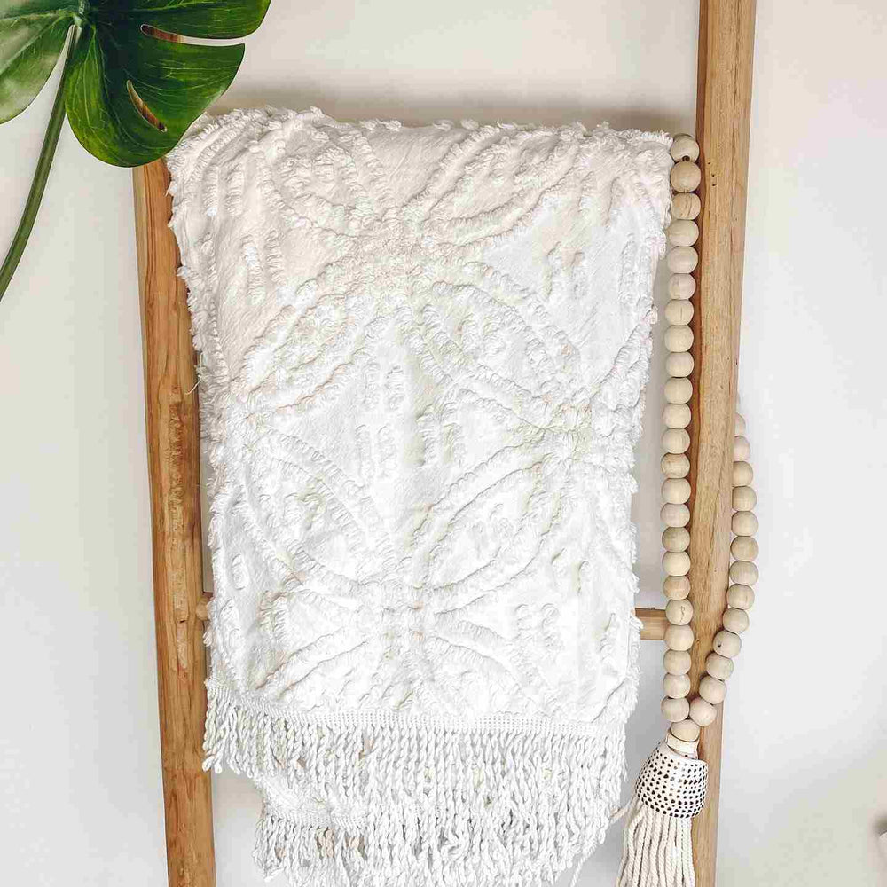 White tufted Darcie cotton throw elegantly displayed on wooden ladder showcasing versatile home styling options